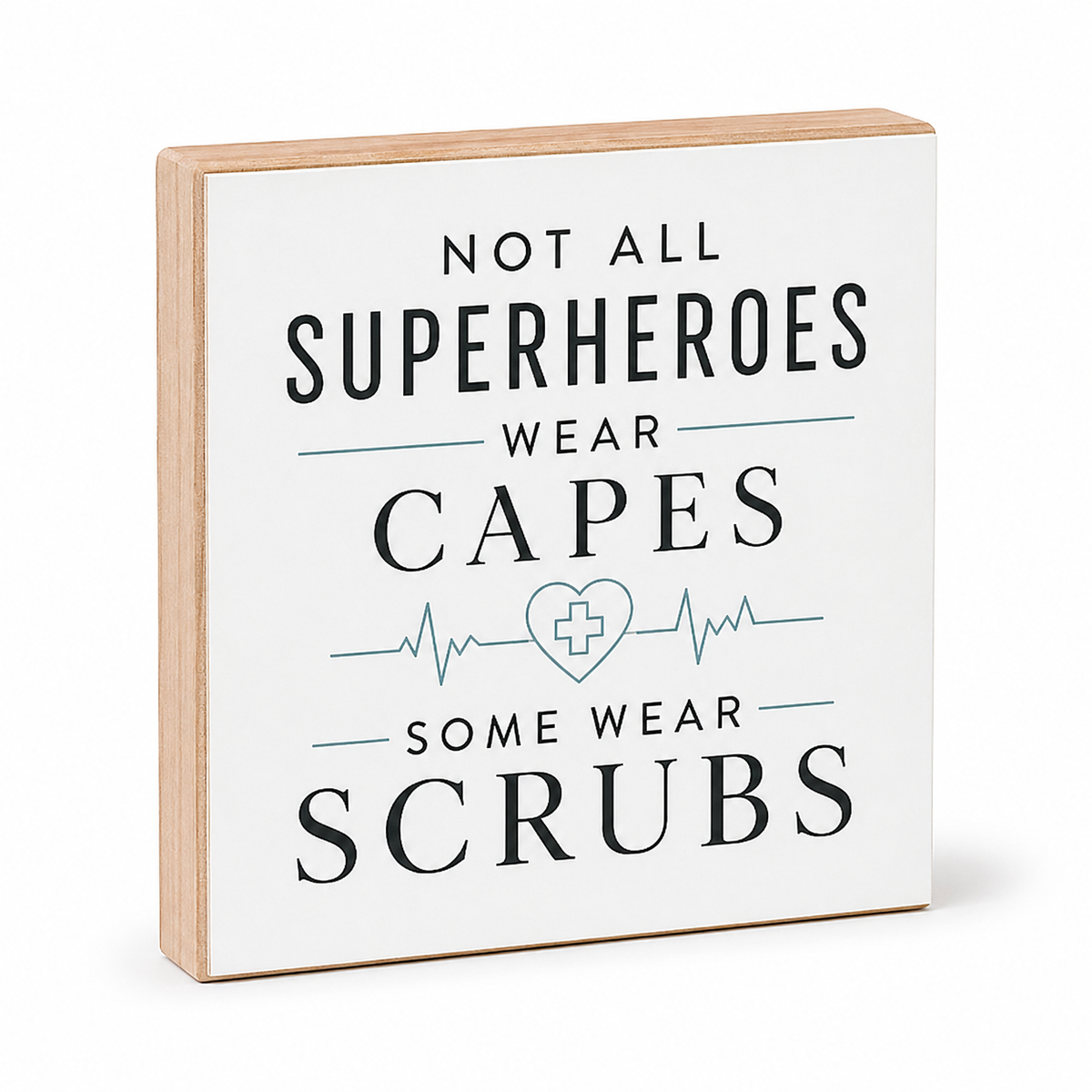 A square decorative wooden sign with a white face and natural wood edges, printed with the phrase 'NOT ALL SUPERHEROES WEAR CAPES SOME WEAR SCRUBS' in dark lettering with a light blue heart monitor line and cross symbol.