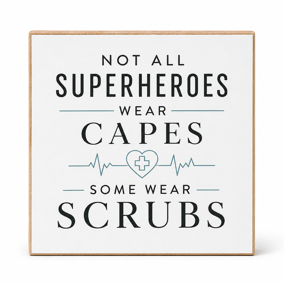 A square decorative wall sign with a light wood border and a white face, printed with the phrase 'NOT ALL SUPERHEROES WEAR CAPES SOME WEAR SCRUBS' in dark gray text with a teal heart monitor and cross graphic, shown on a white background.