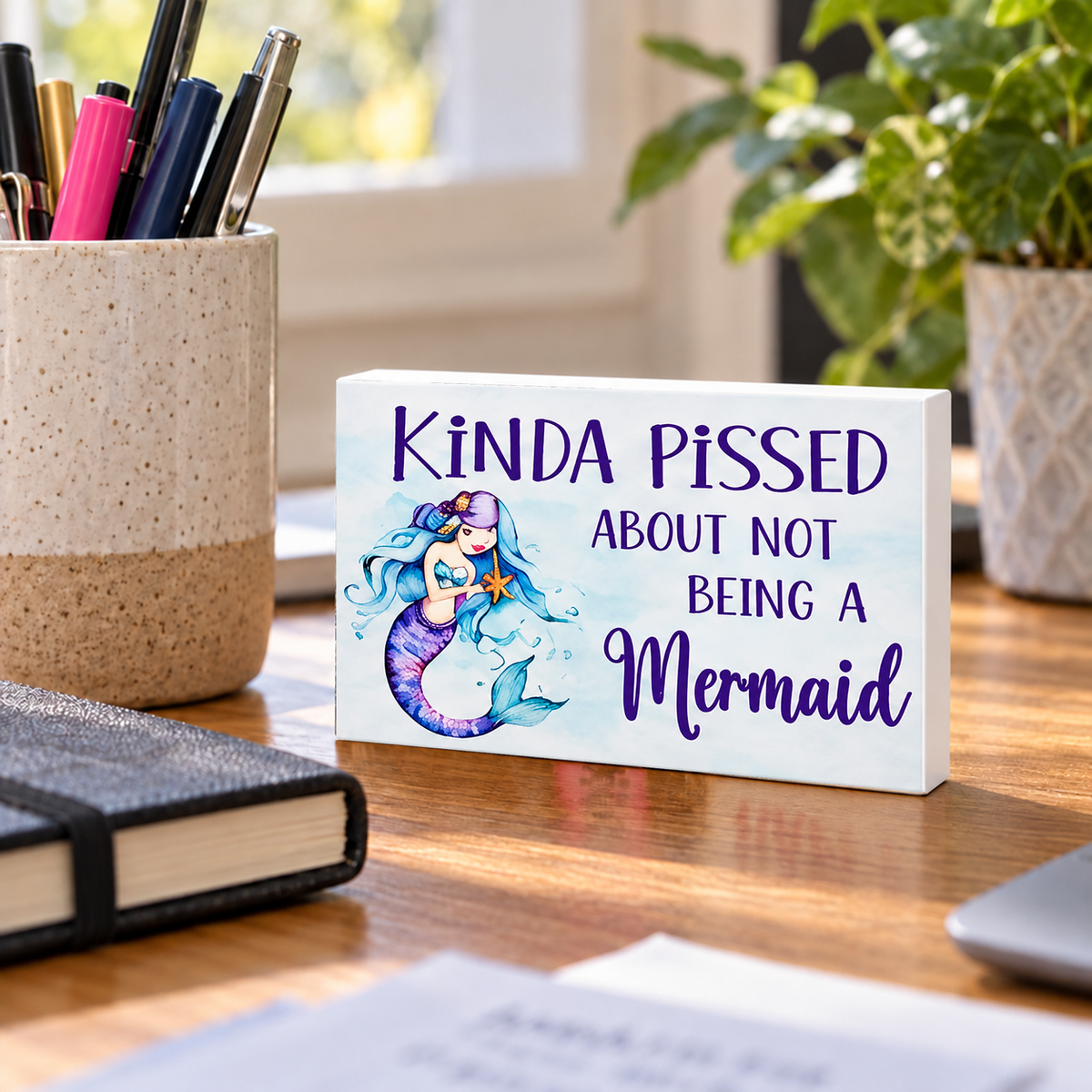 Kinda Pissed About Not Being a Mermaid mini sign standing on a desk with white PVC edges.