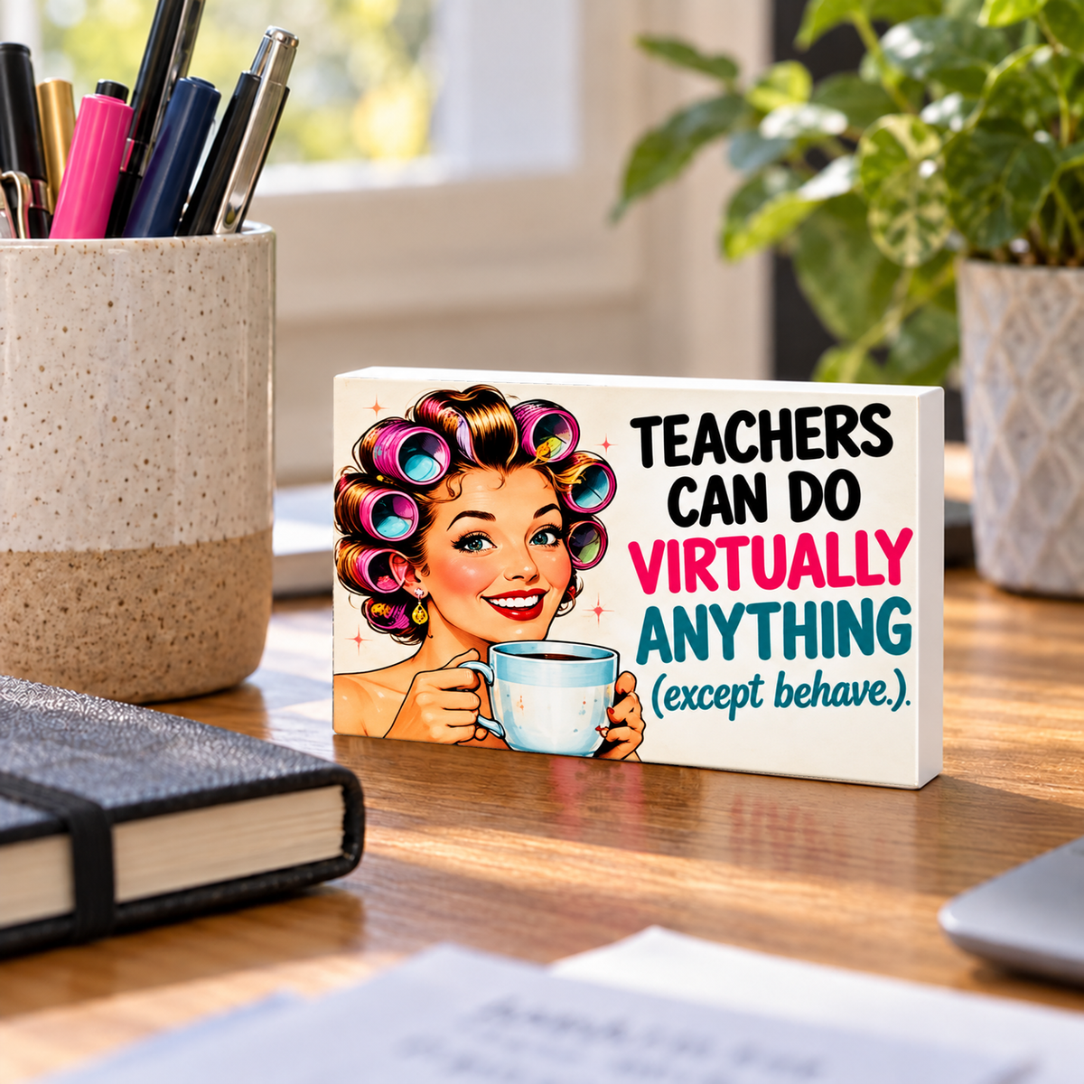 Teachers Can Do Virtually Anything (Except Behave) mini sign standing on a desk with white PVC edges.