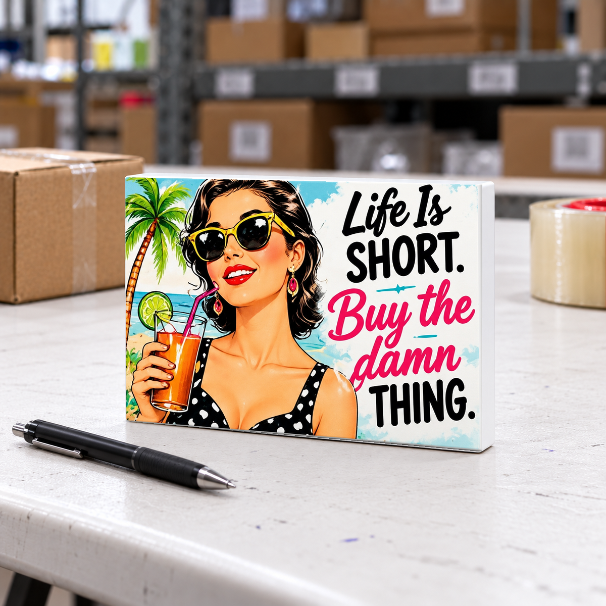 Life Is Short. Buy the Damn Thing magnet and mini sign on a white folding warehouse table.