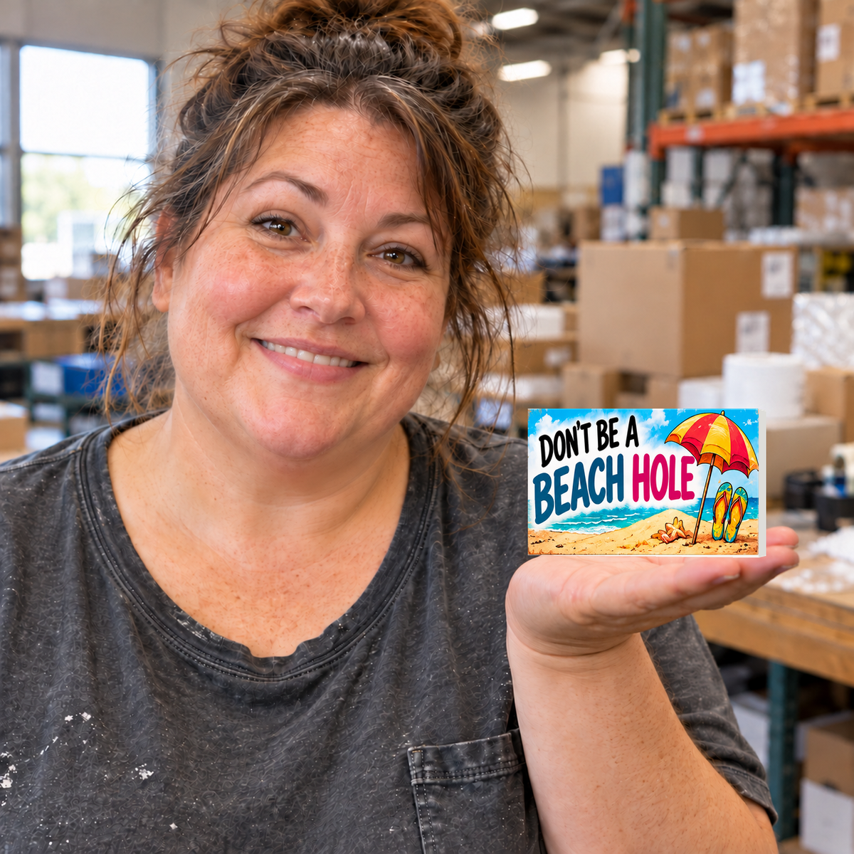 Don't Be a Beach Hole rectangular magnet held on an open palm in a warehouse setting.