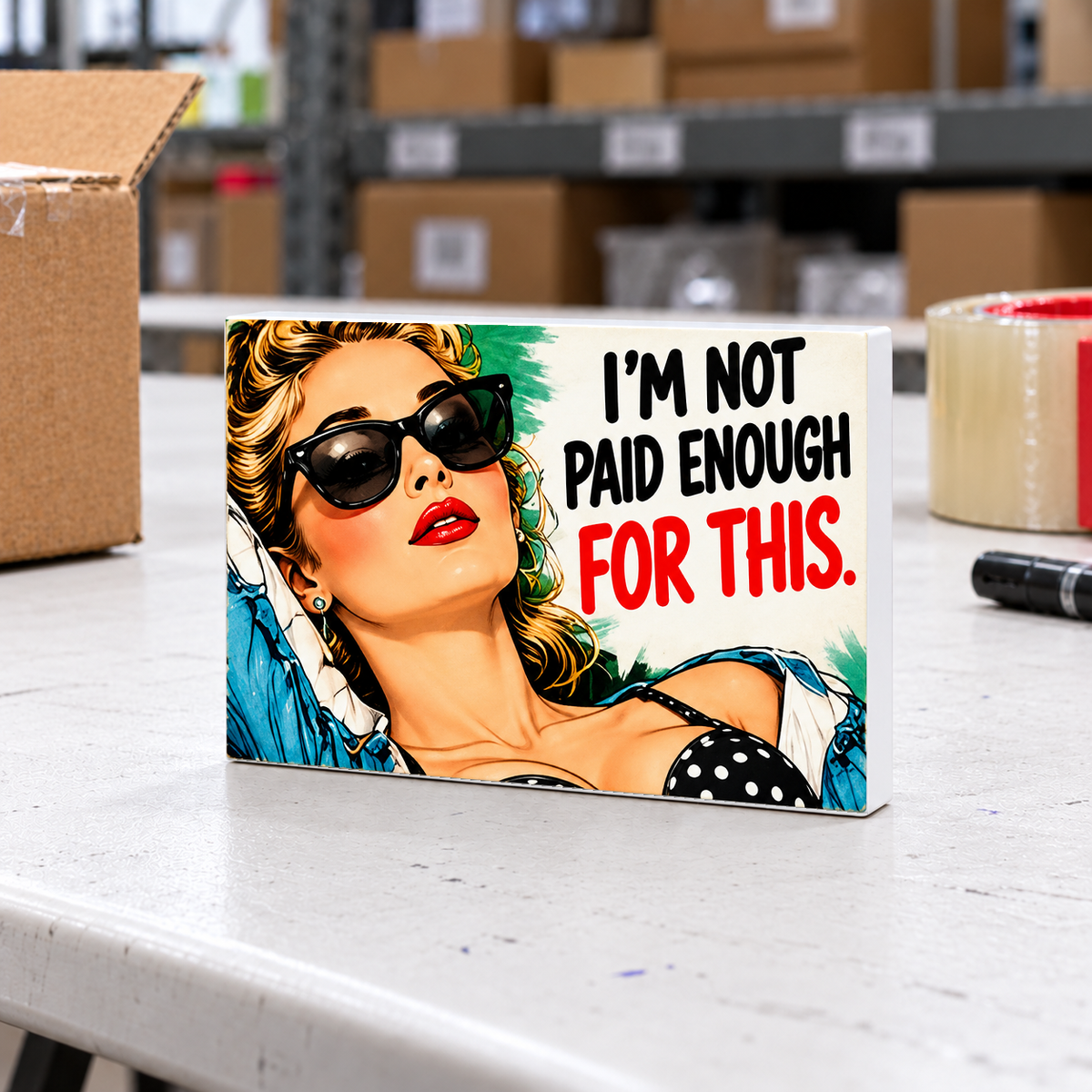 I'm Not Paid Enough for This magnet and mini sign on a white folding warehouse table.