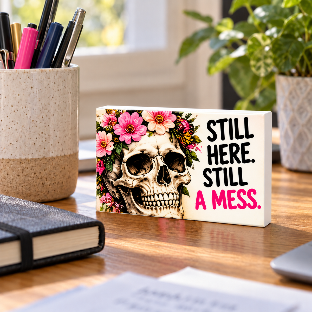 Still Here Still a Mess mini sign standing on a desk with white PVC edges.