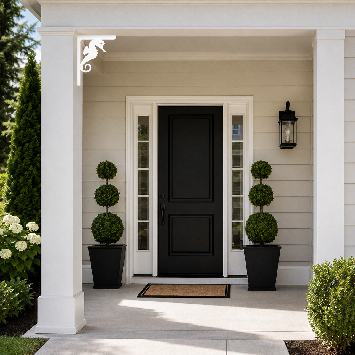 A modern black front door with white trim, set on a covered porch with white columns, black planter boxes with topiary trees, and a beige siding exterior.
