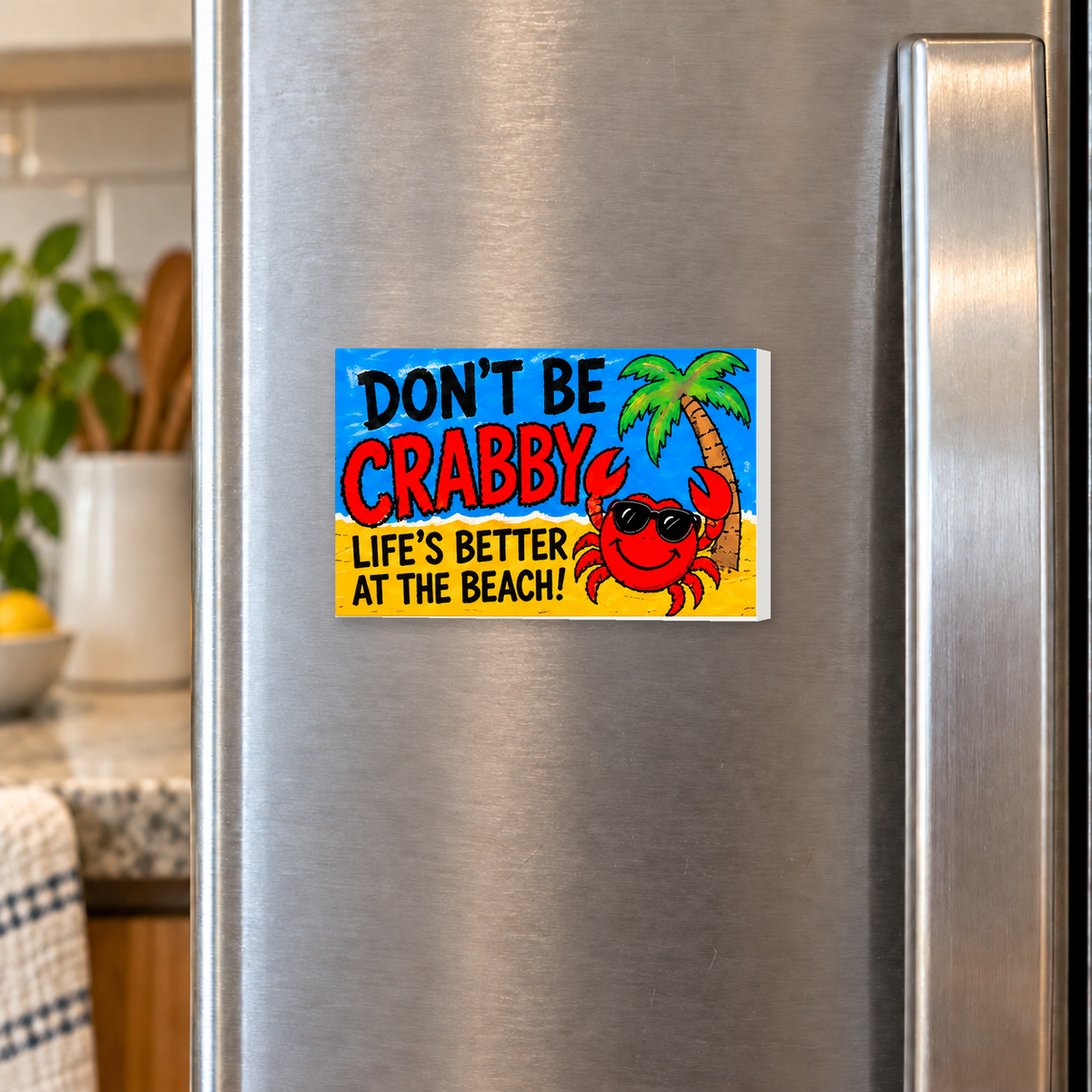 Don't Be Crabby Life's Better at the Beach rectangular magnet shown front-facing on a refrigerator.