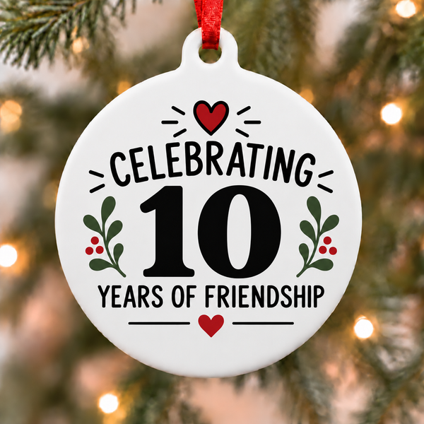 White round Christmas ornament celebrating 10 years of friendship with red hearts and green botanical accents hanging on a Christmas tree